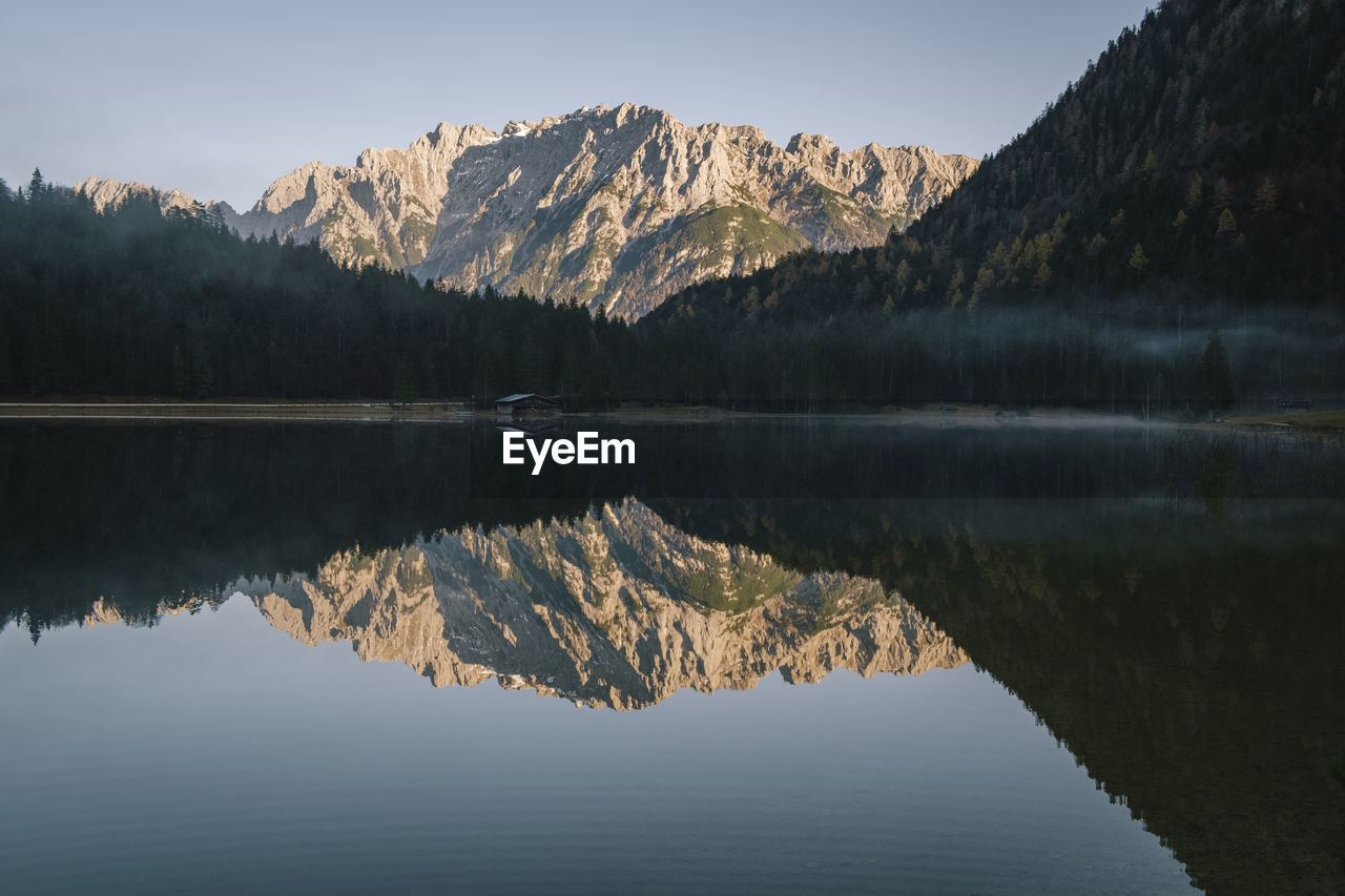 REFLECTION OF MOUNTAINS IN LAKE AGAINST SKY