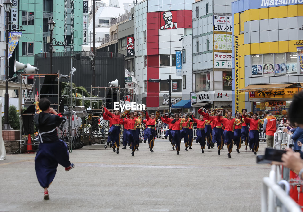 PEOPLE WALKING ON ROAD AGAINST BUILDINGS IN CITY