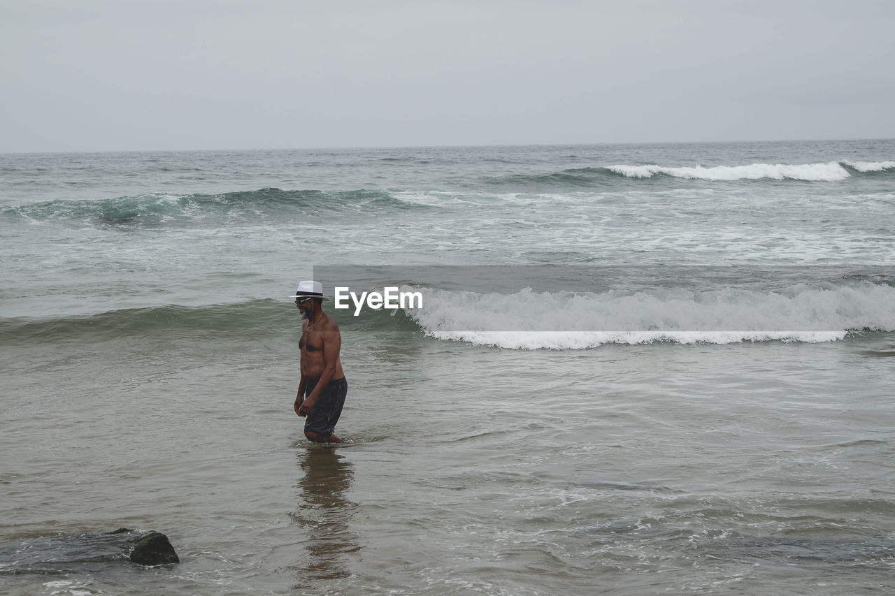 Shirtless man standing in sea