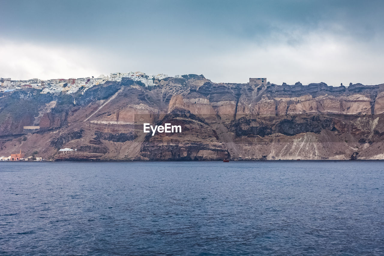 Scenic view of sea by mountain against sky