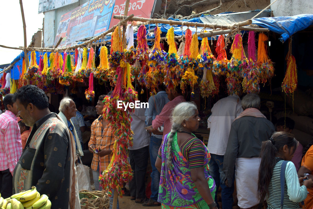 REAR VIEW OF PEOPLE STANDING AGAINST MULTI COLORED TRADITIONAL CLOTHING