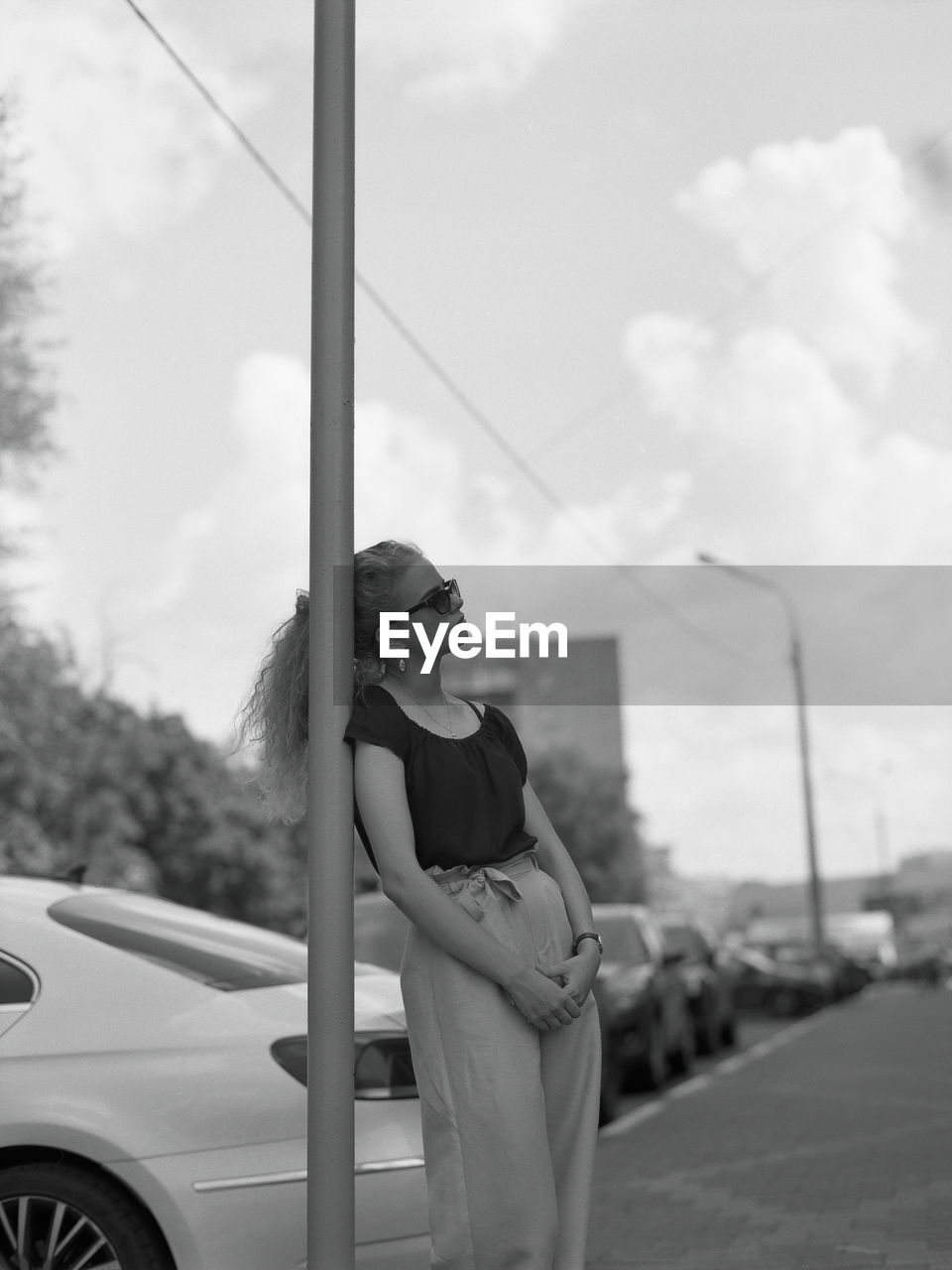 Young woman looking away while leaning against pole