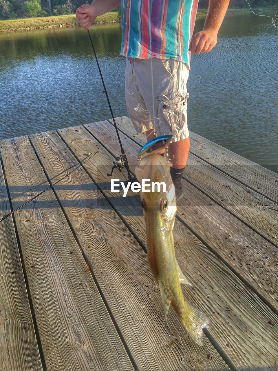 REAR VIEW OF MAN STANDING ON PIER