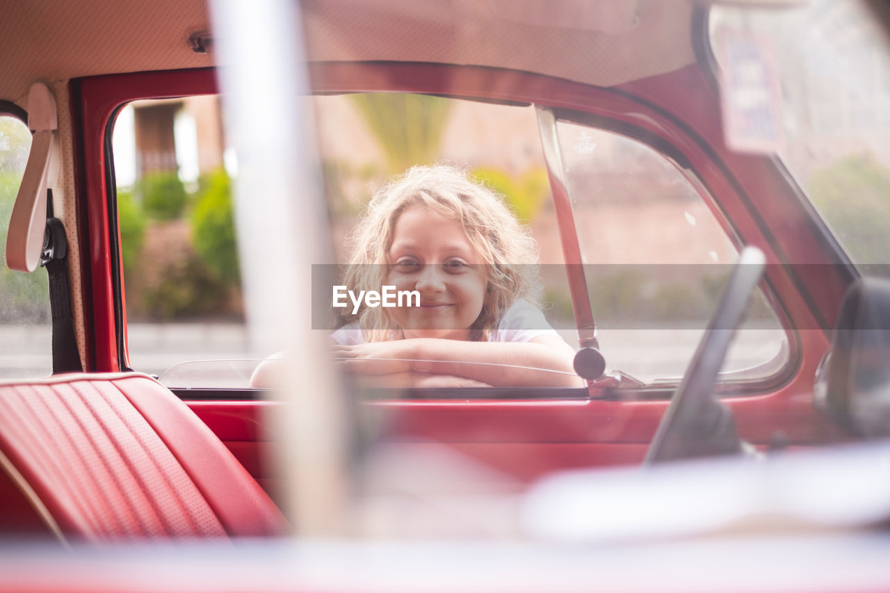 Portrait of smiling girl leaning on car door