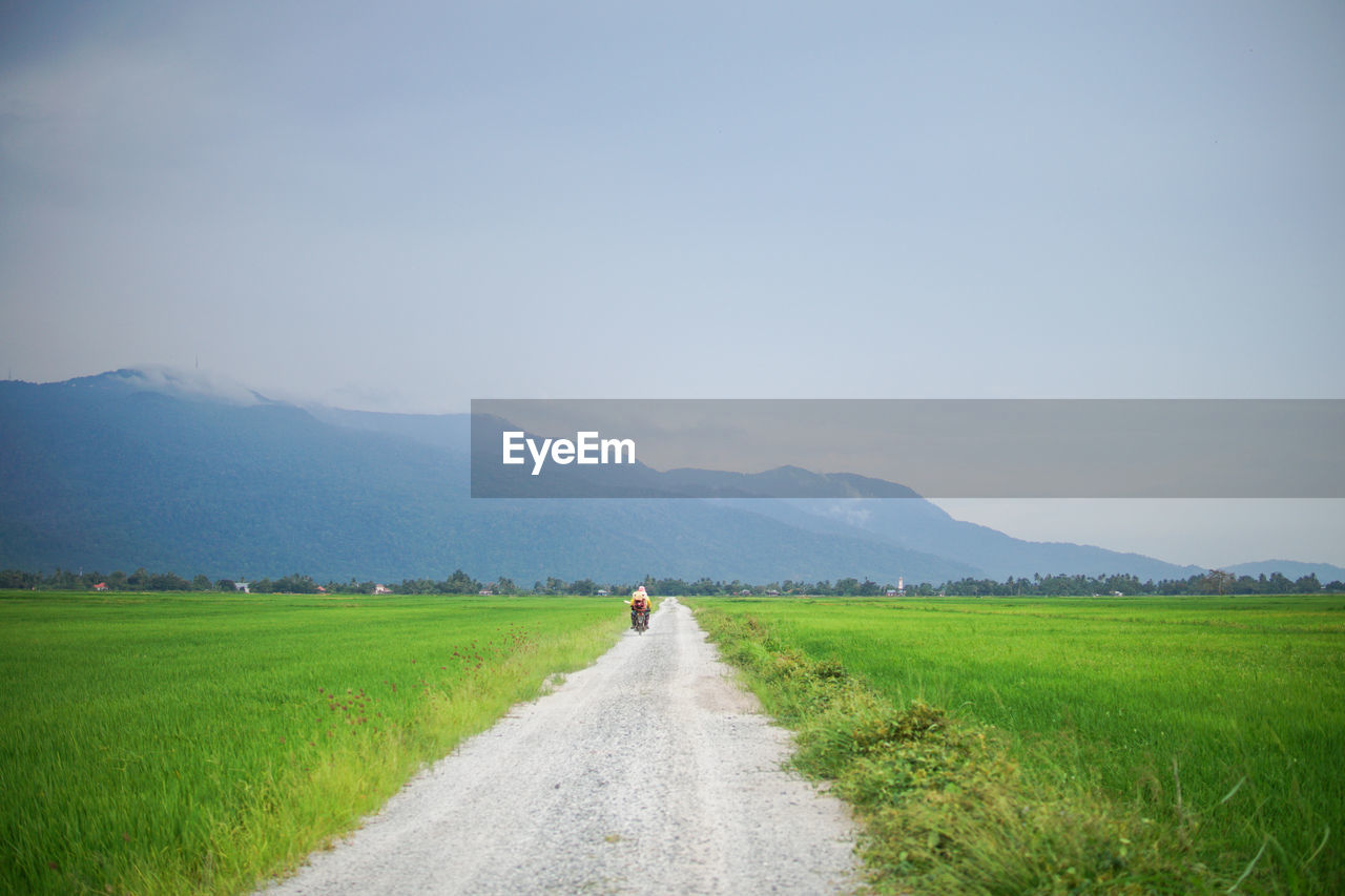 ROAD PASSING THROUGH FIELD AGAINST SKY