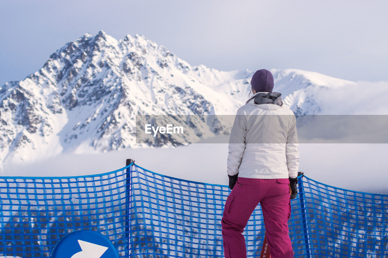 Rear view of woman standing against snowcapped mountain