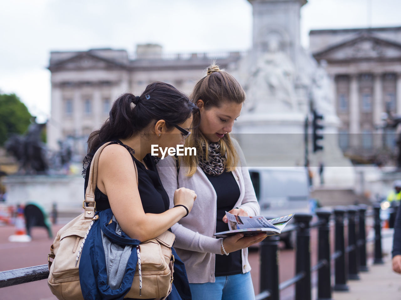 Female friends reading guidebook in city