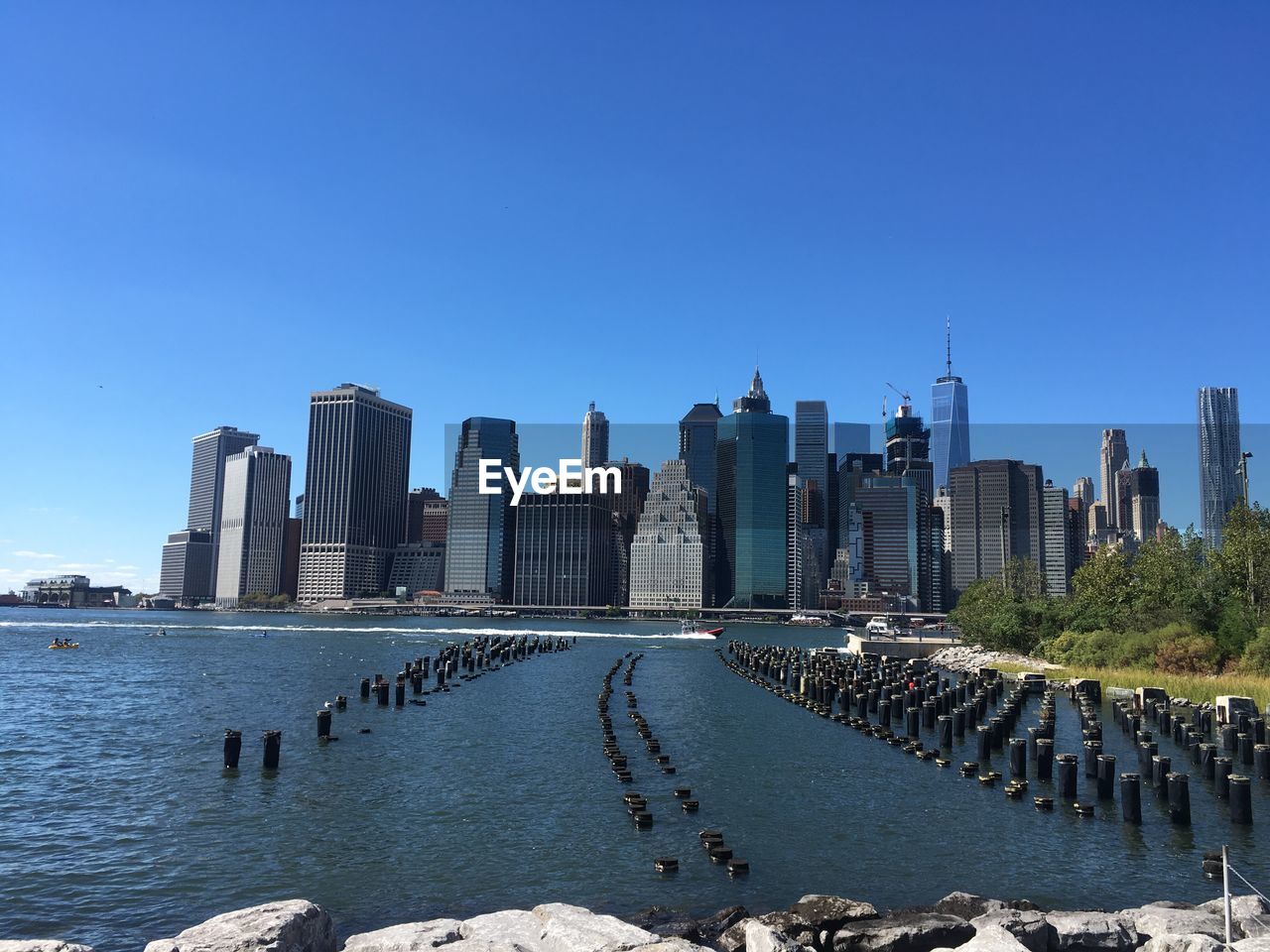 Sea in front of cityscape against clear blue sky