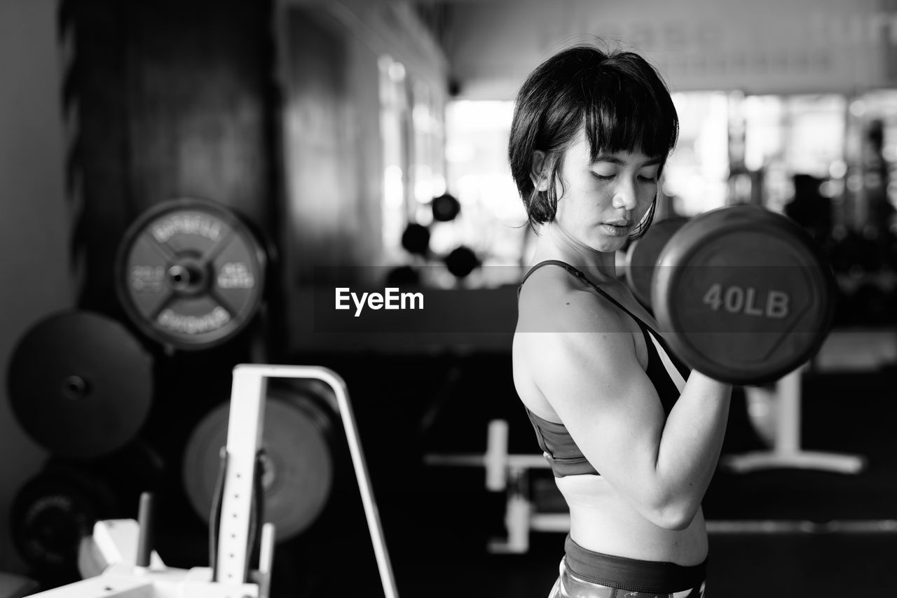 Side view of young woman exercising at gym