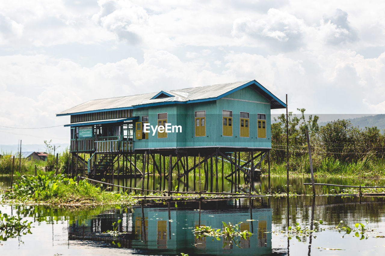 House by lake against sky