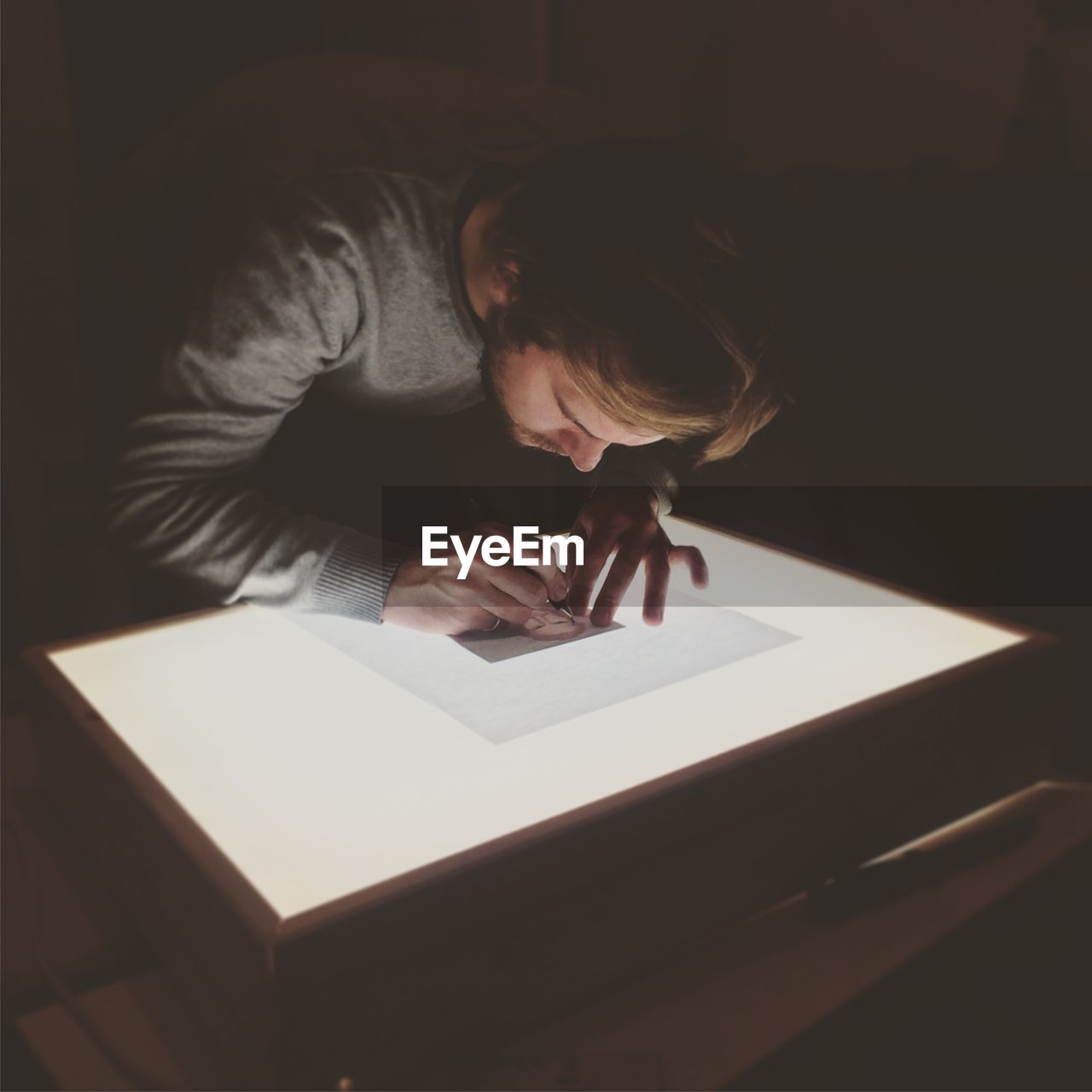 Close-up of man drawing against table light