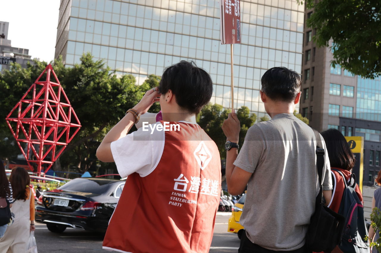 REAR VIEW OF PEOPLE WALKING ON ZEBRA CROSSING