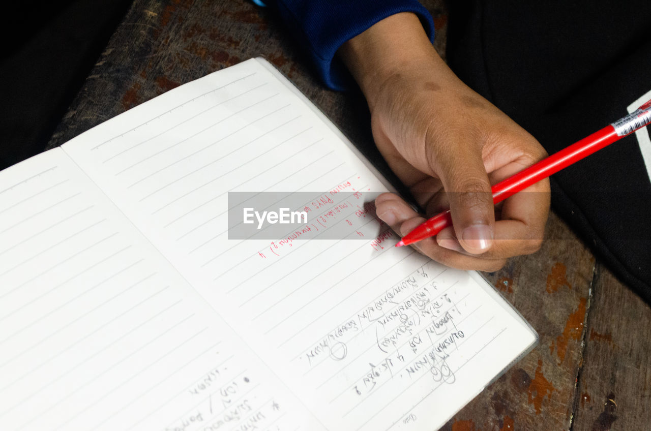 HIGH ANGLE VIEW OF HAND HOLDING BOOK WITH TEXT