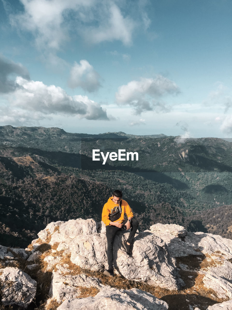 People on rock by mountain against sky