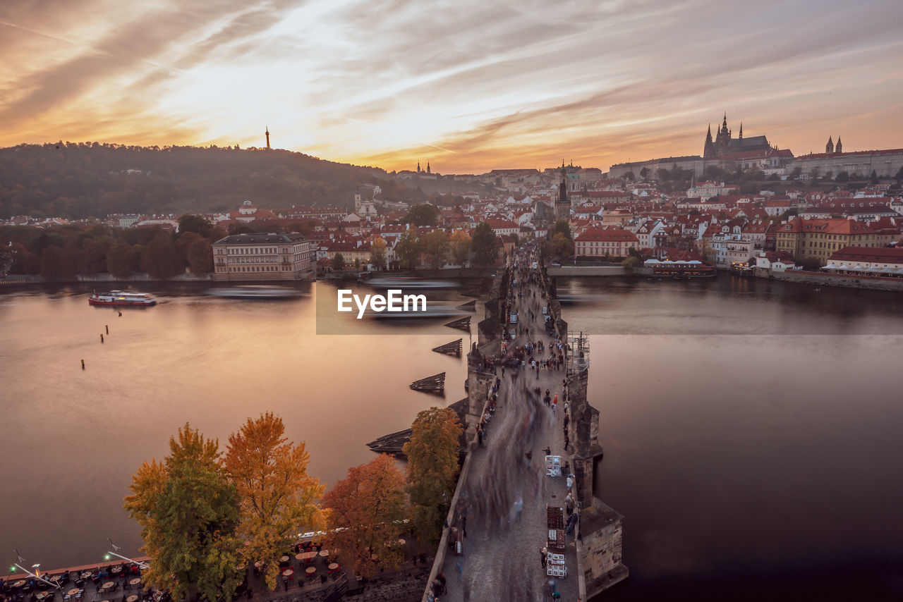 River amidst buildings in city against sky during sunset