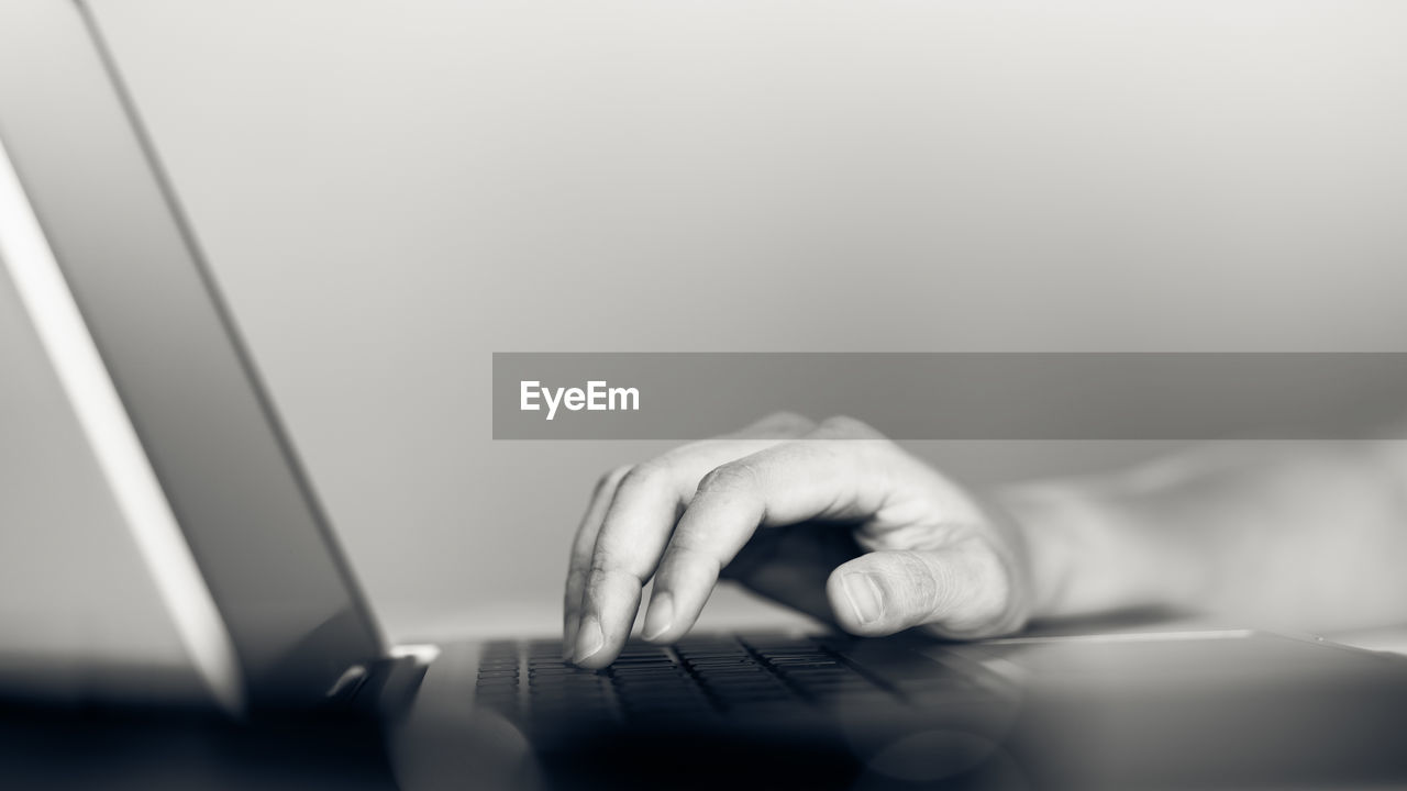 CLOSE-UP OF PERSON USING SMART PHONE ON TABLE