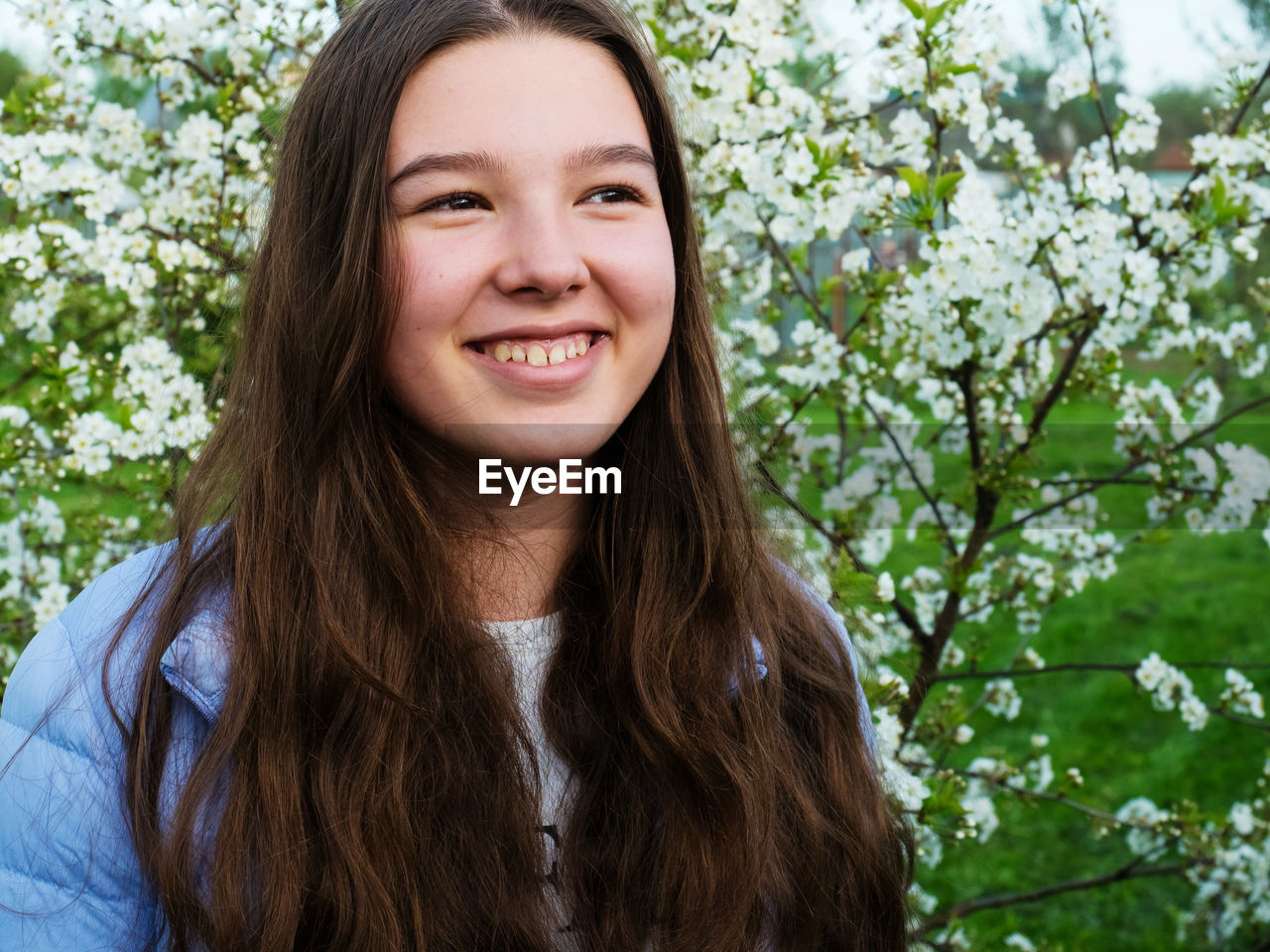 Smiling girl standing against flowering plant