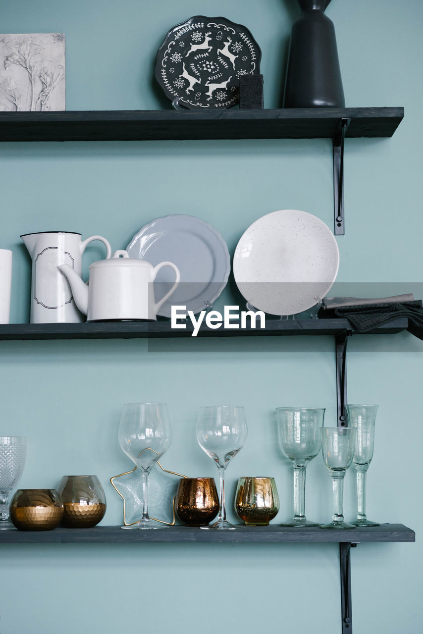Kitchen utensils on the shelves glass glasses, gold glasses, plates, teapots