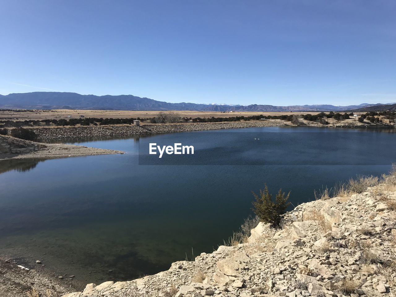 SCENIC VIEW OF LAKE BY MOUNTAINS AGAINST CLEAR SKY