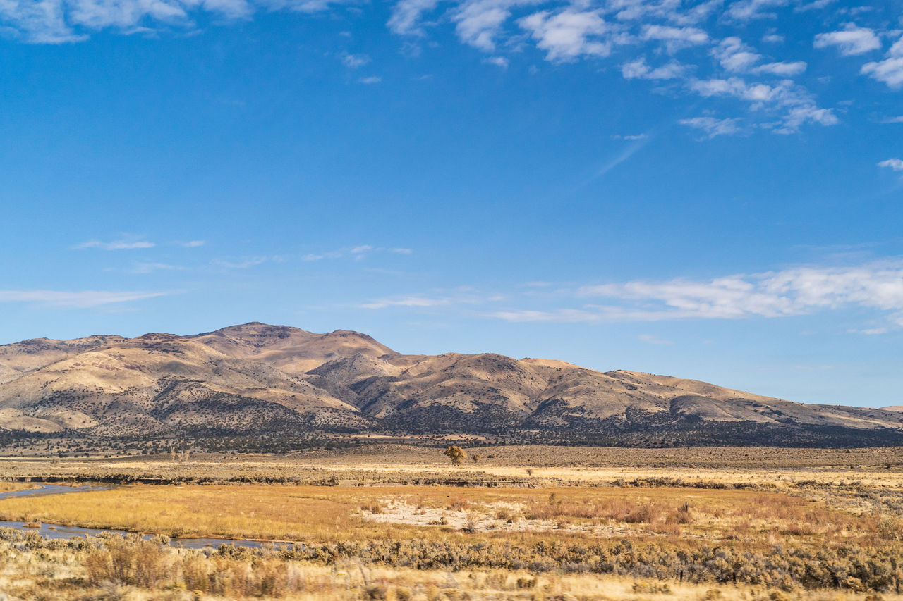 Beautiful arid rolling hills landscape in northern california against clouds and blue sky