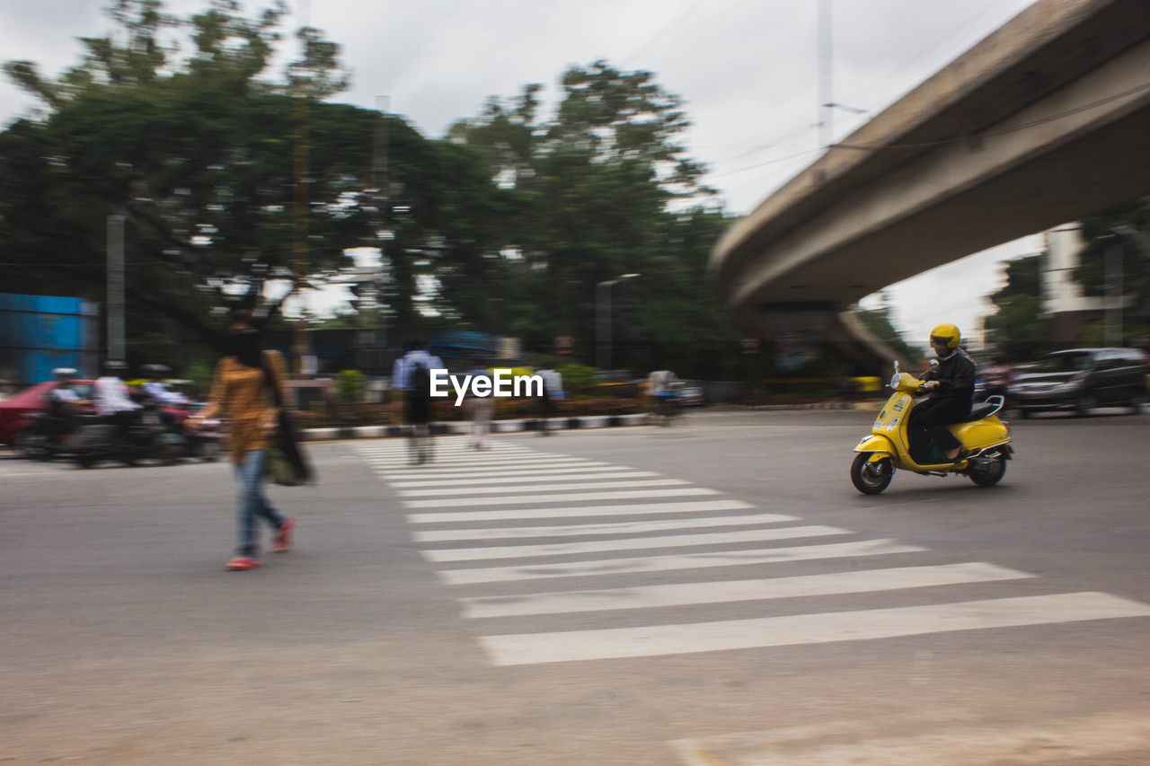 WOMAN WALKING ON ROAD IN CITY