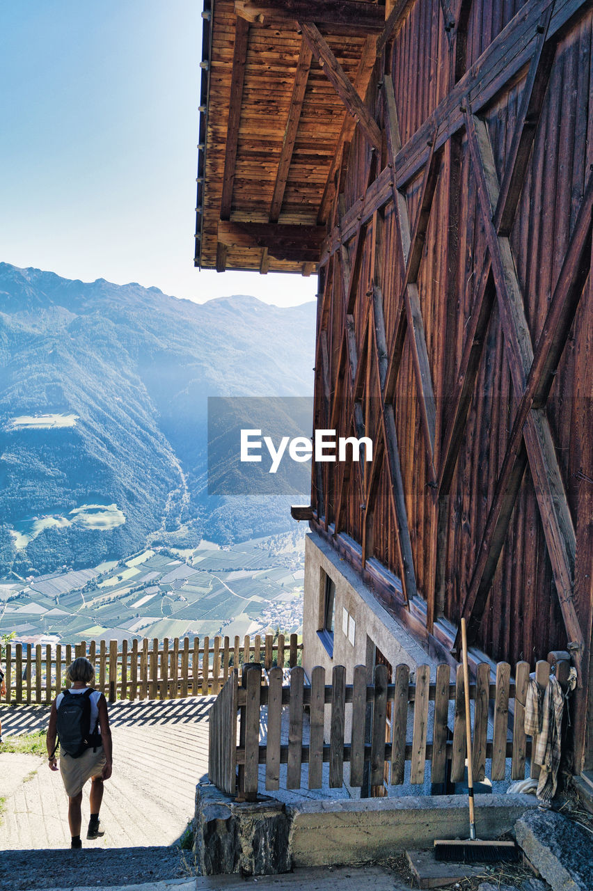 REAR VIEW OF WOMAN ON SNOWCAPPED MOUNTAIN AGAINST SKY