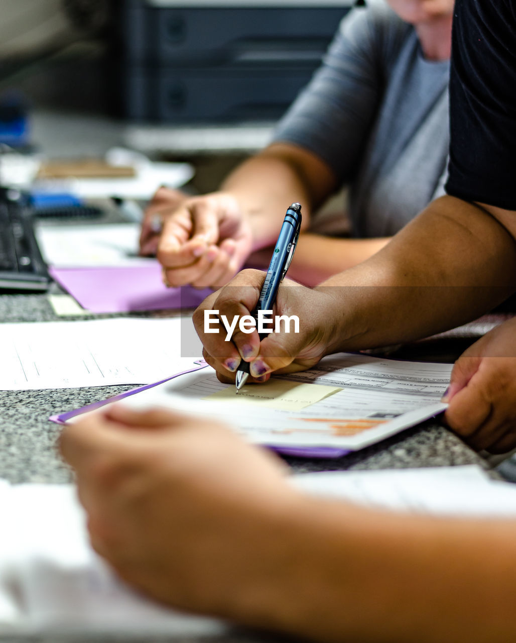 Cropped image of people writing on papers at table