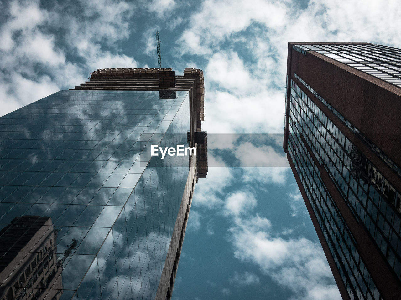 Low angle view of modern glass buildings against cloudy sky