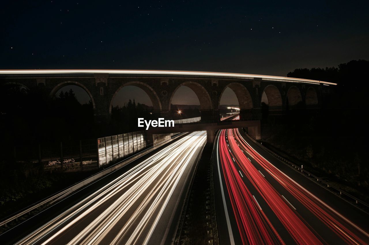 Light trails on road against sky at night