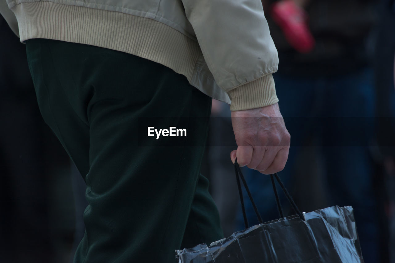 Midsection of man with shopping bag in city