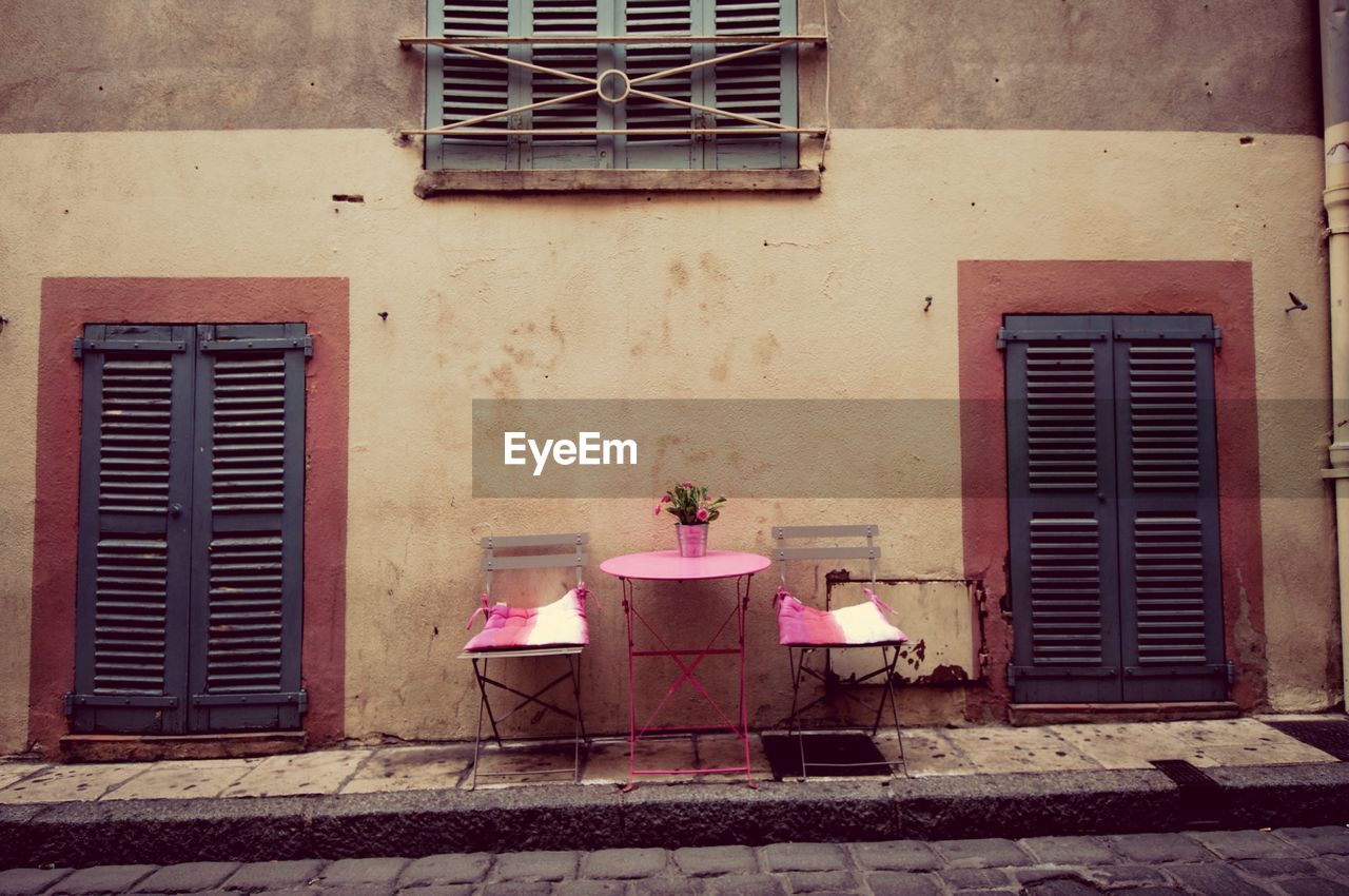 Chairs and table on sidewalk against building