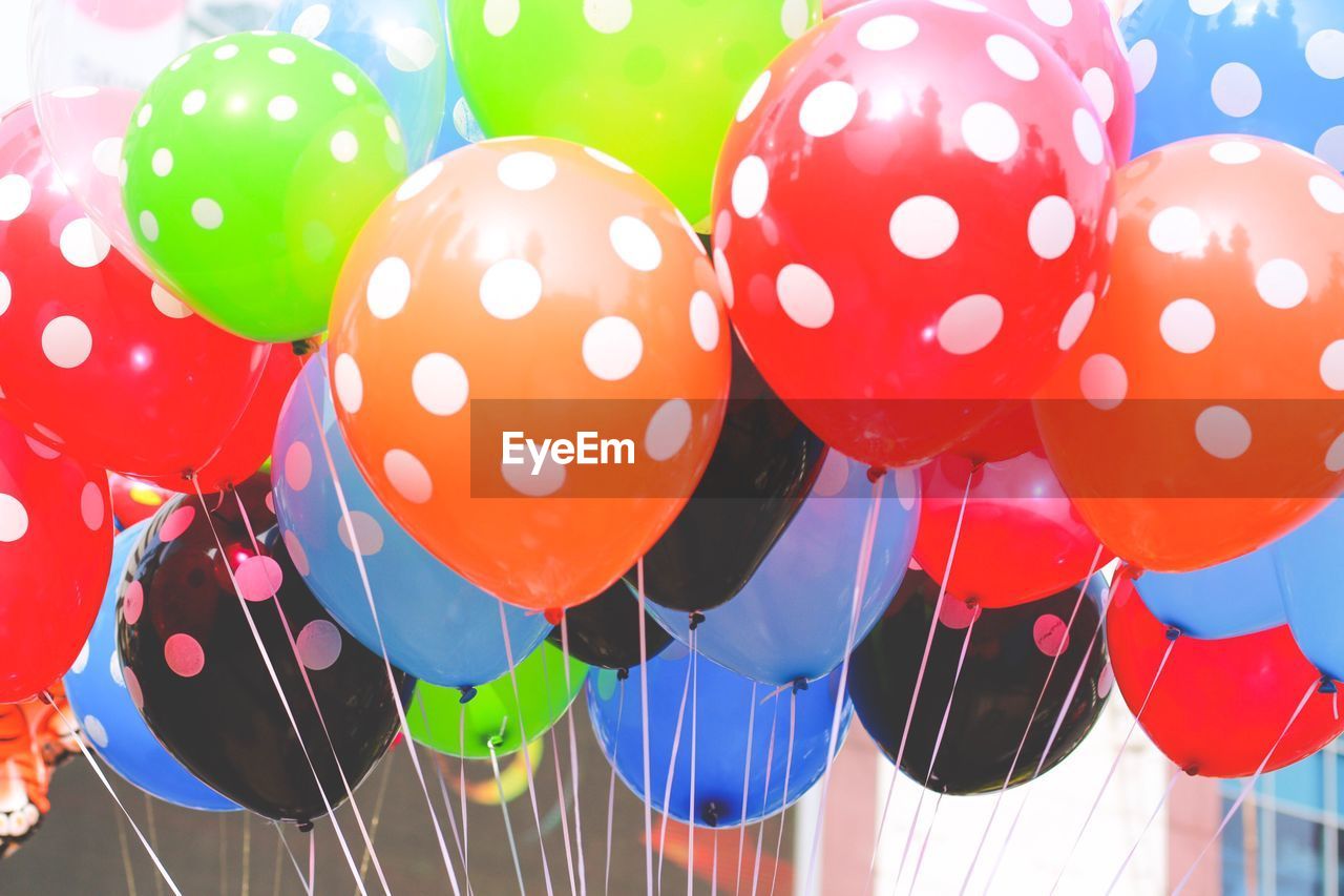 CLOSE-UP OF MULTI COLORED BALLOONS HANGING ON CLOTHESLINE