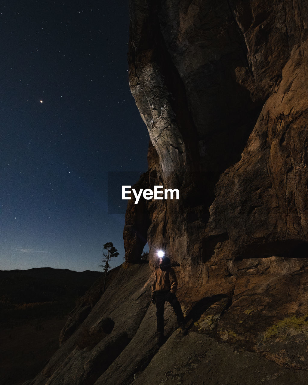 Man standing on rock against sky at night
