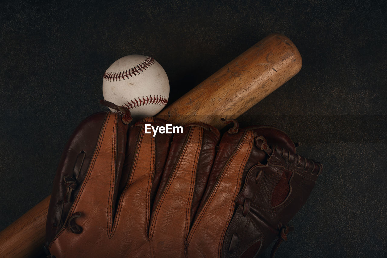 Close up one old baseball ball, wooden bat and worn leather vintage glove