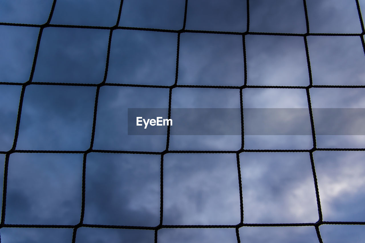 LOW ANGLE VIEW OF METAL FENCE AGAINST CLOUDY SKY