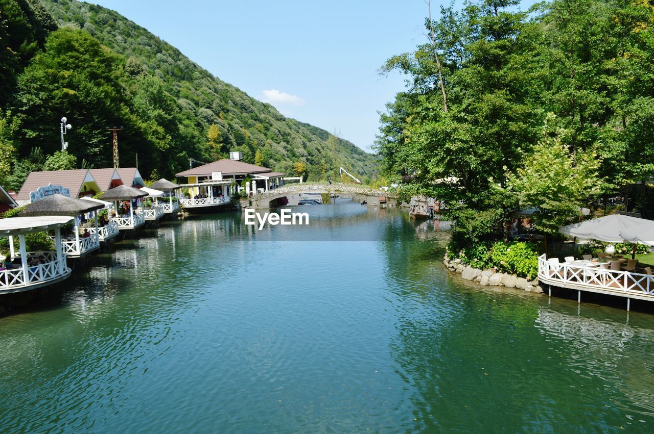 SCENIC VIEW OF CANAL BY BUILDINGS AND TREES AGAINST SKY