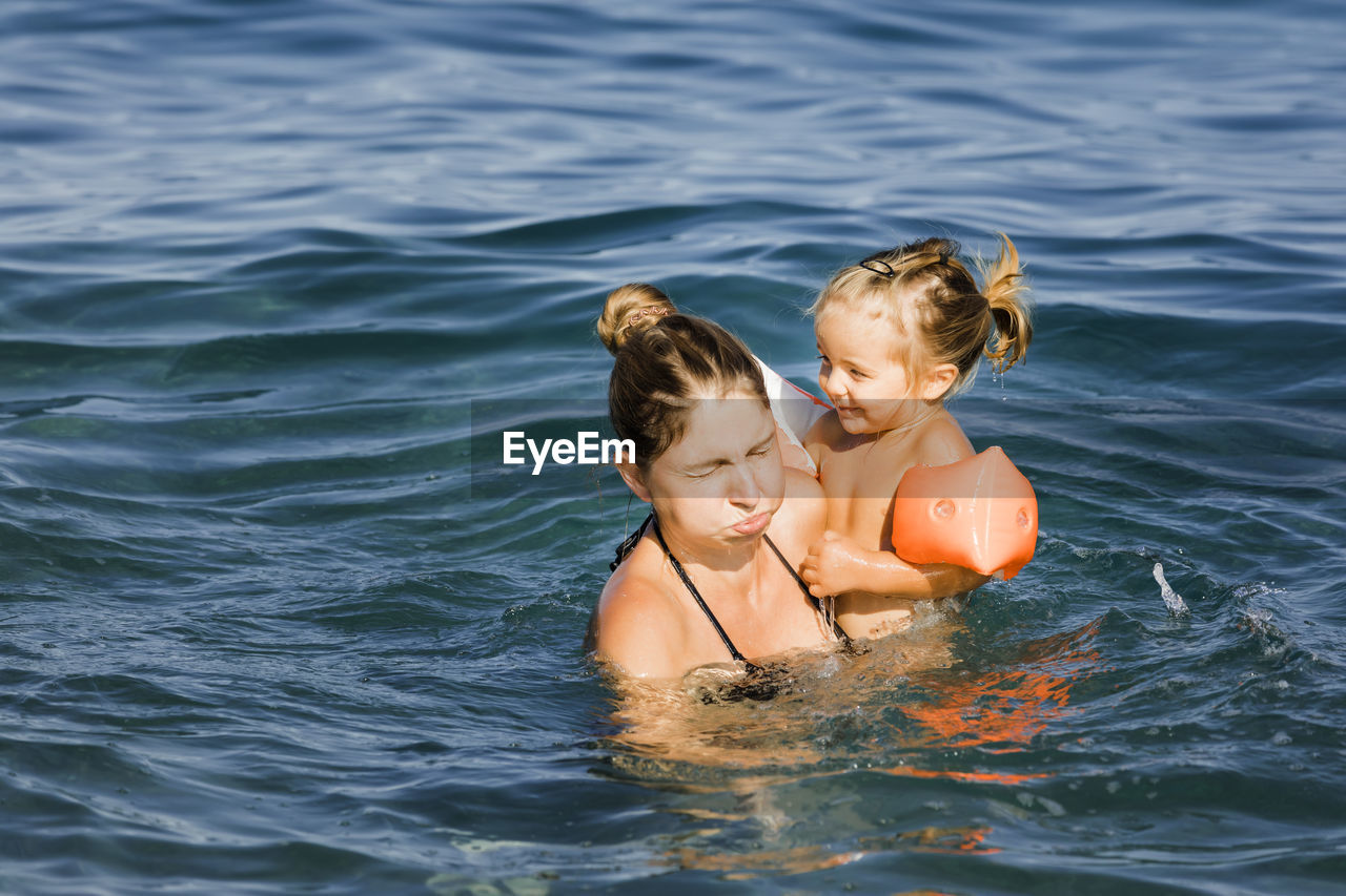 Woman and daughter swimming in sea