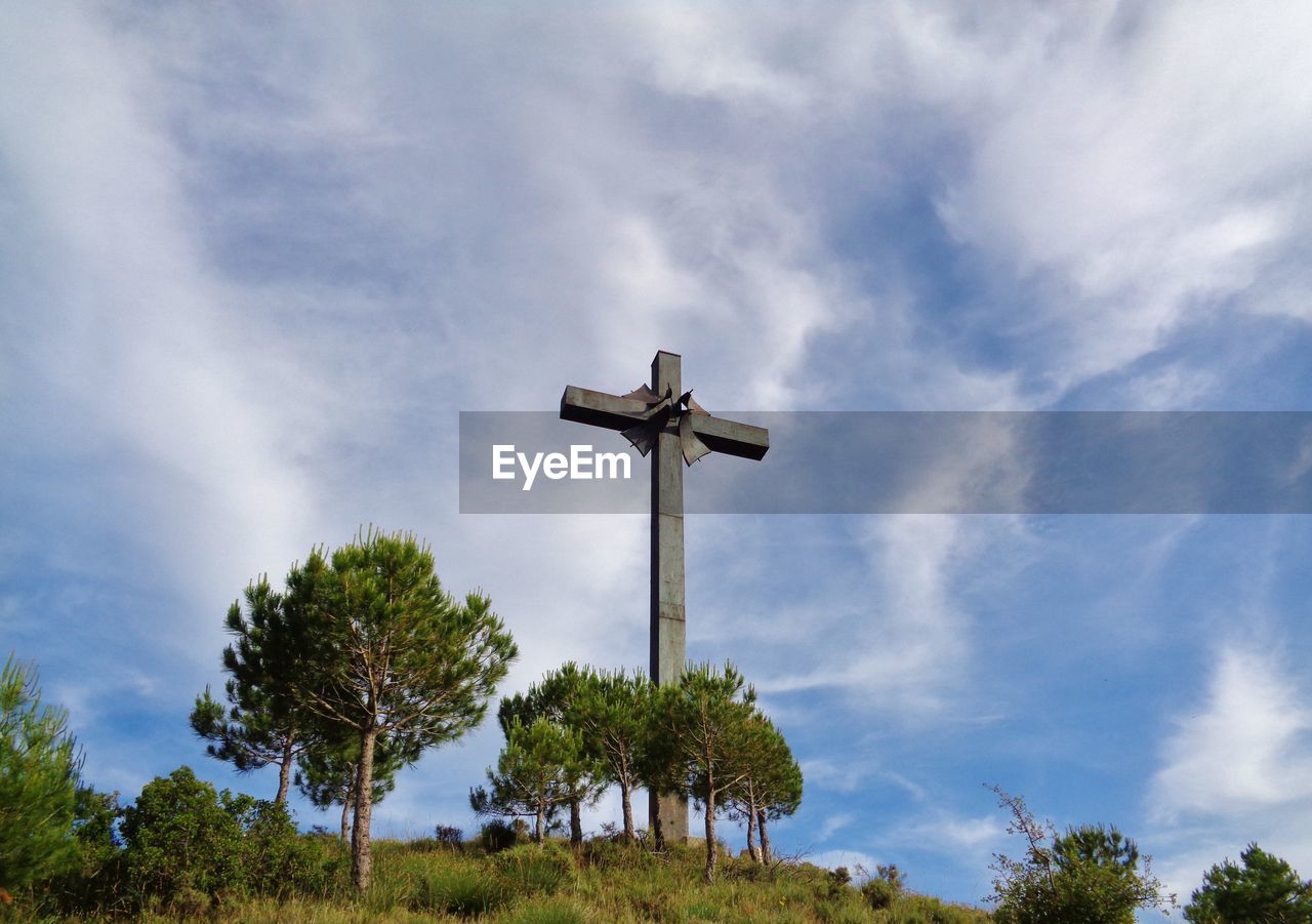 LOW ANGLE VIEW OF CROSS AGAINST TREES