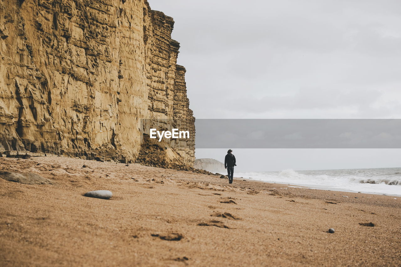 Rear view of man walking on beach