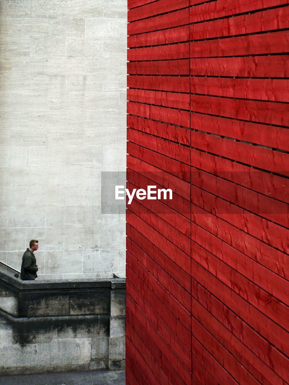 MAN AGAINST RED WALL