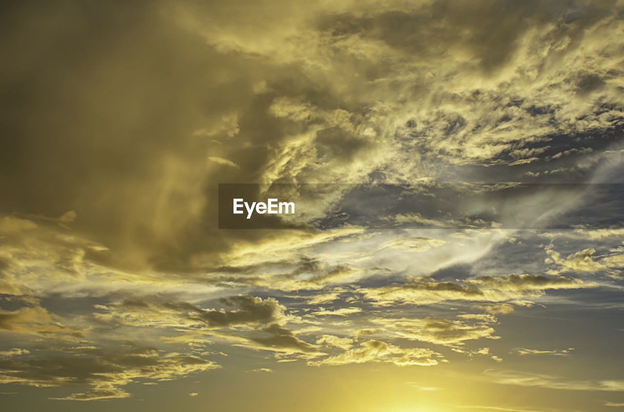 Low angle view of sunlight streaming through clouds