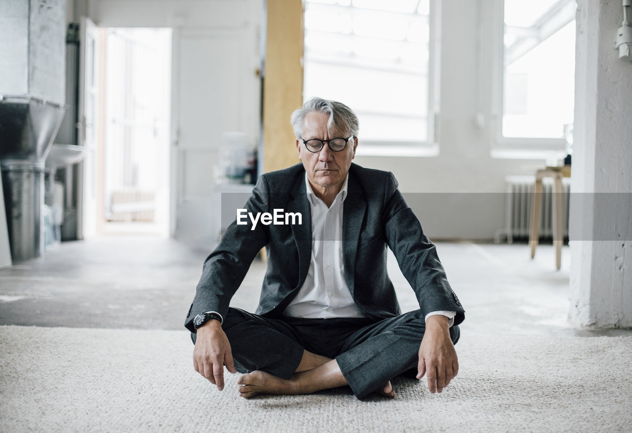 Senior businessman sitting on floor meditating