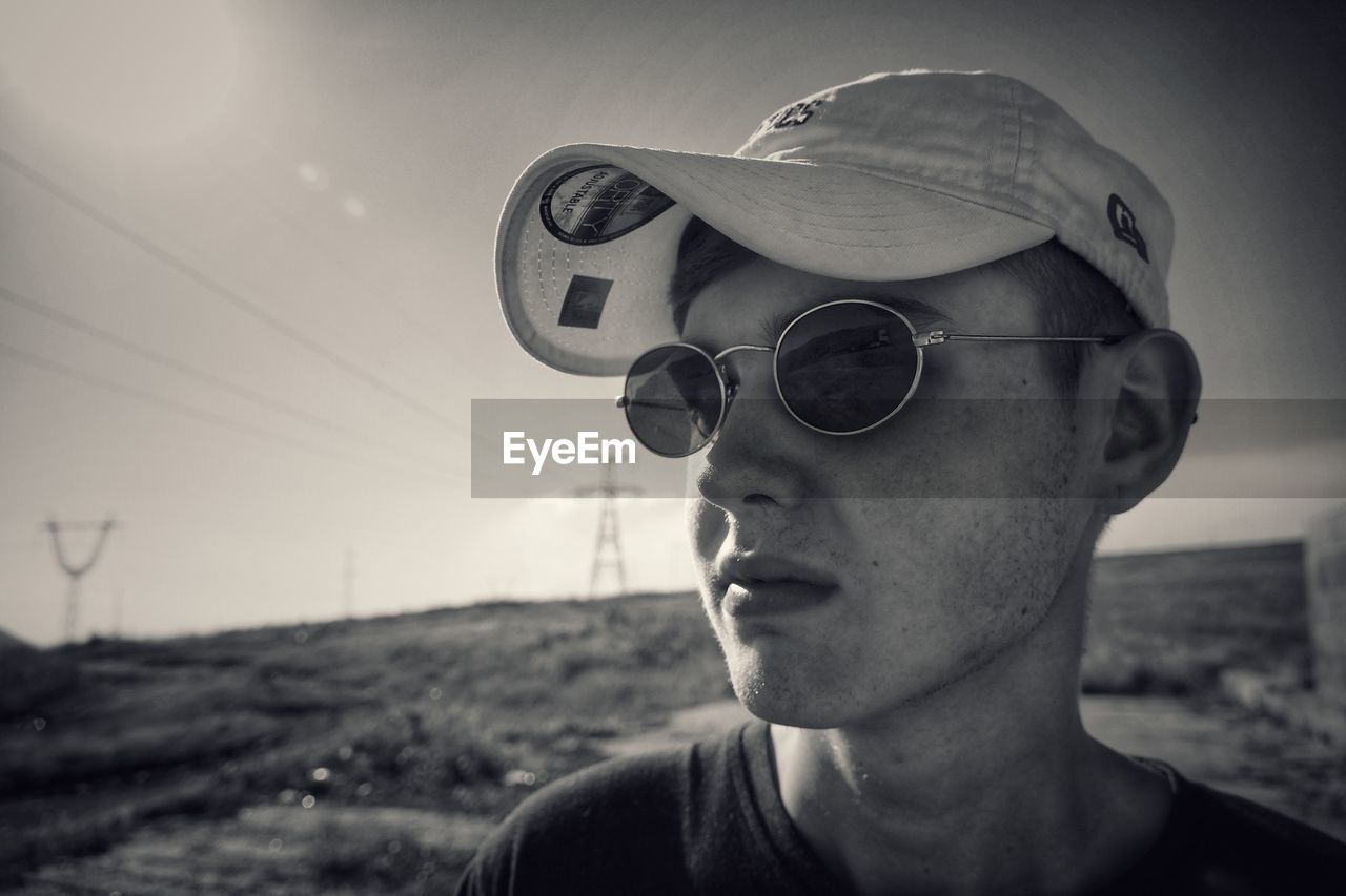 CLOSE-UP PORTRAIT OF YOUNG MAN WEARING SUNGLASSES