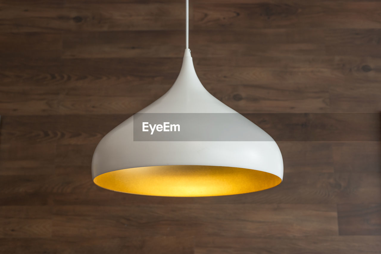 Close-up of pendant light hanging against wooden wall