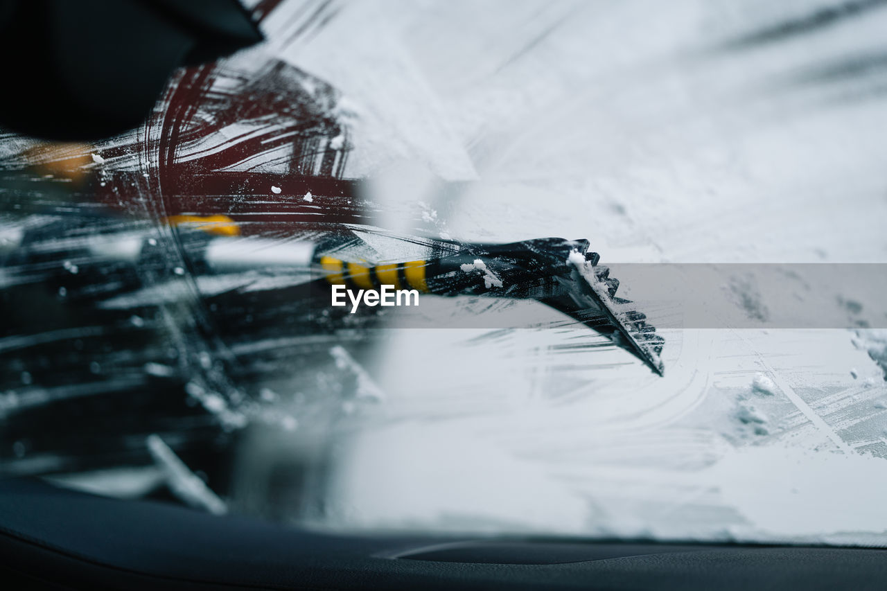 High angle view of snow tool cleaning car windshield in winter