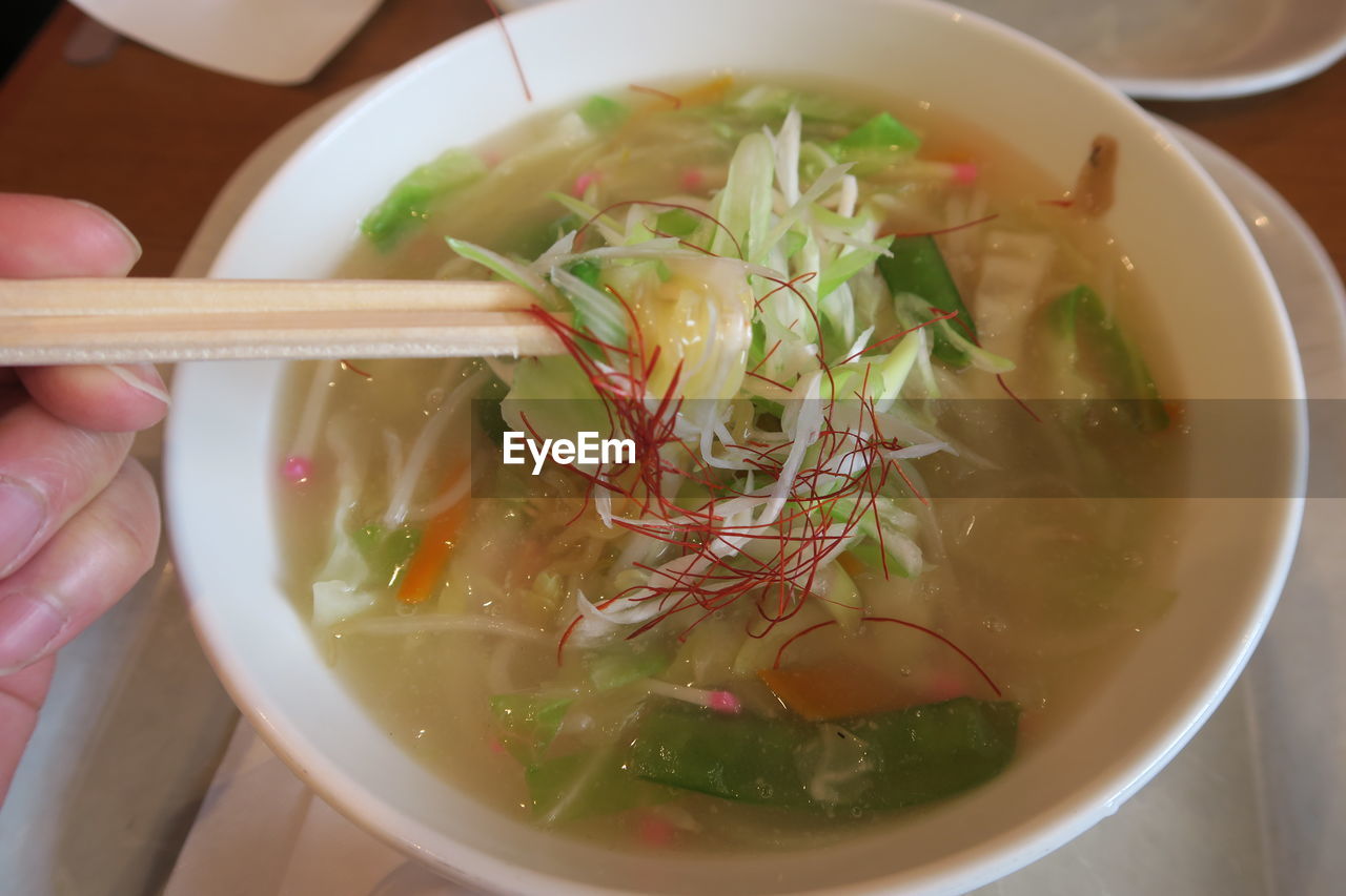 CLOSE-UP OF HAND HOLDING SOUP