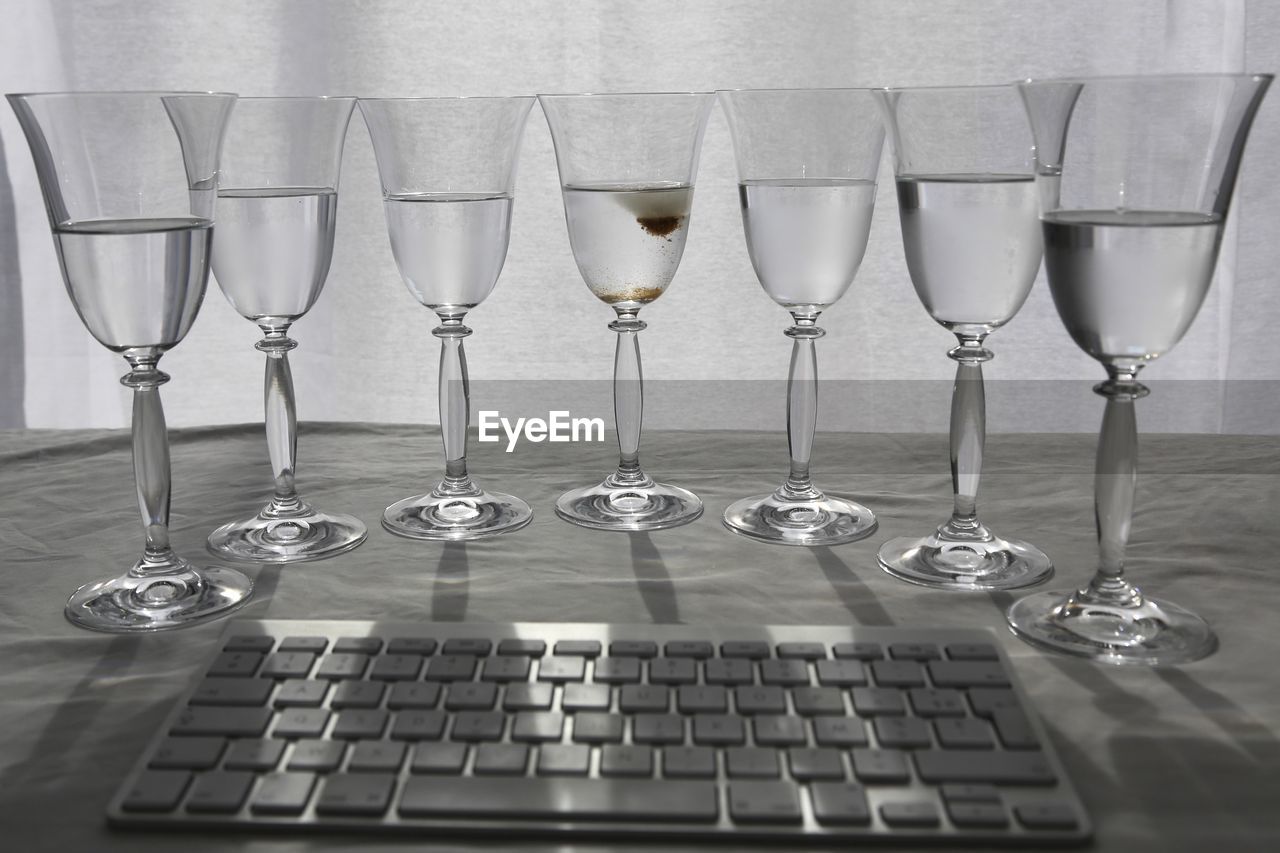 Wineglasses arranged in front of computer keyboard