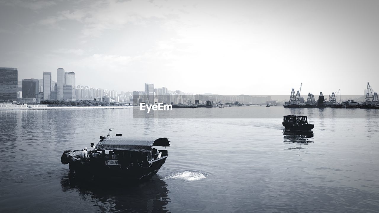 BOATS IN RIVER WITH CITY IN BACKGROUND