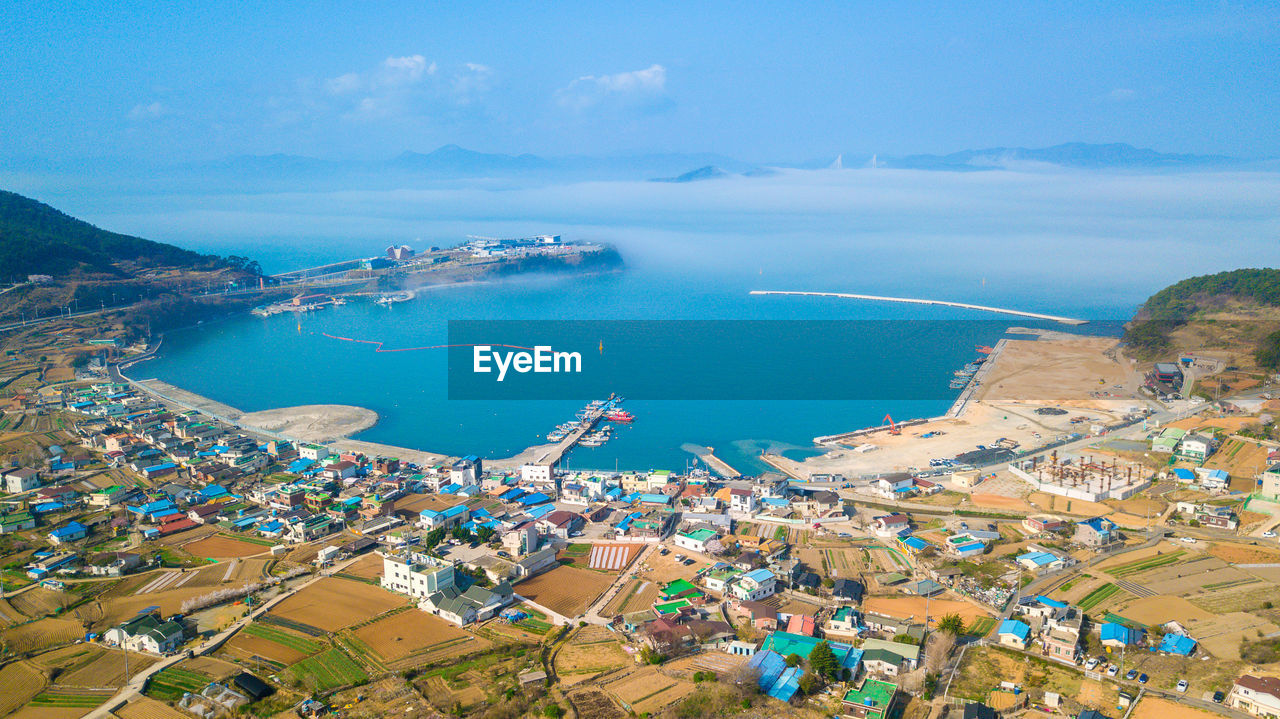 High angle view of city by sea and buildings against sky