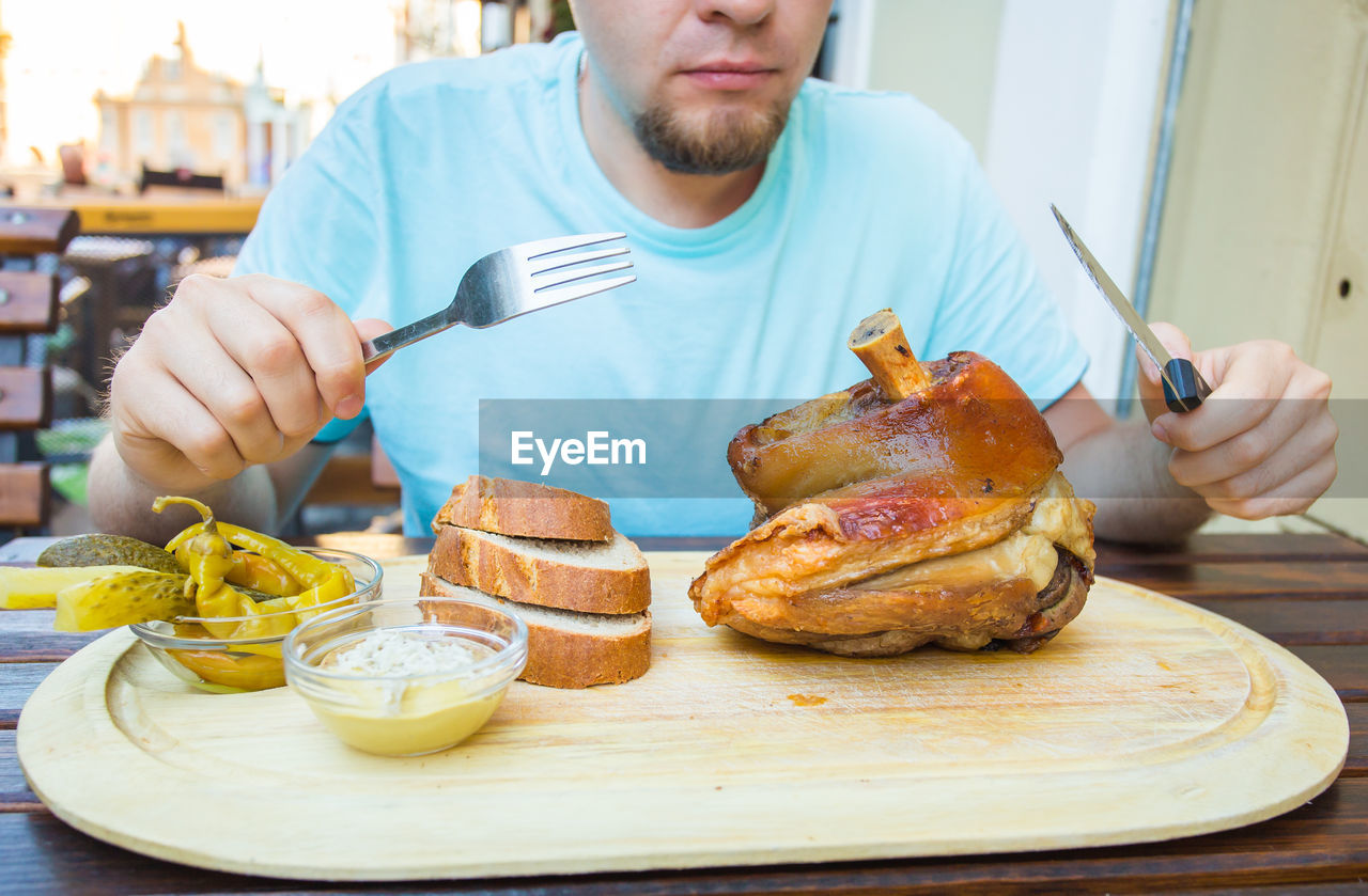 MIDSECTION OF MAN PREPARING FOOD ON TABLE